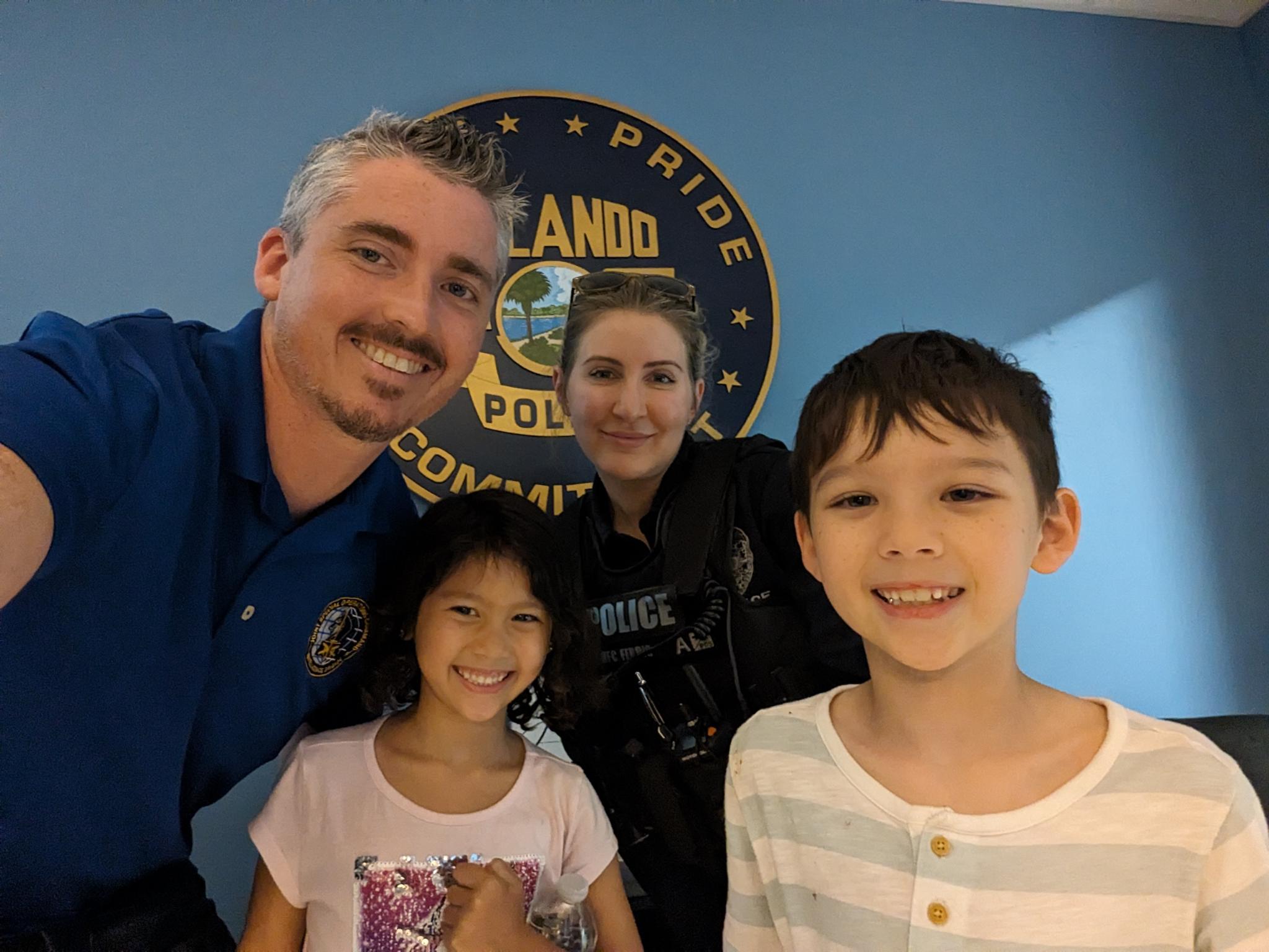 Smiling group at police department, blue background.