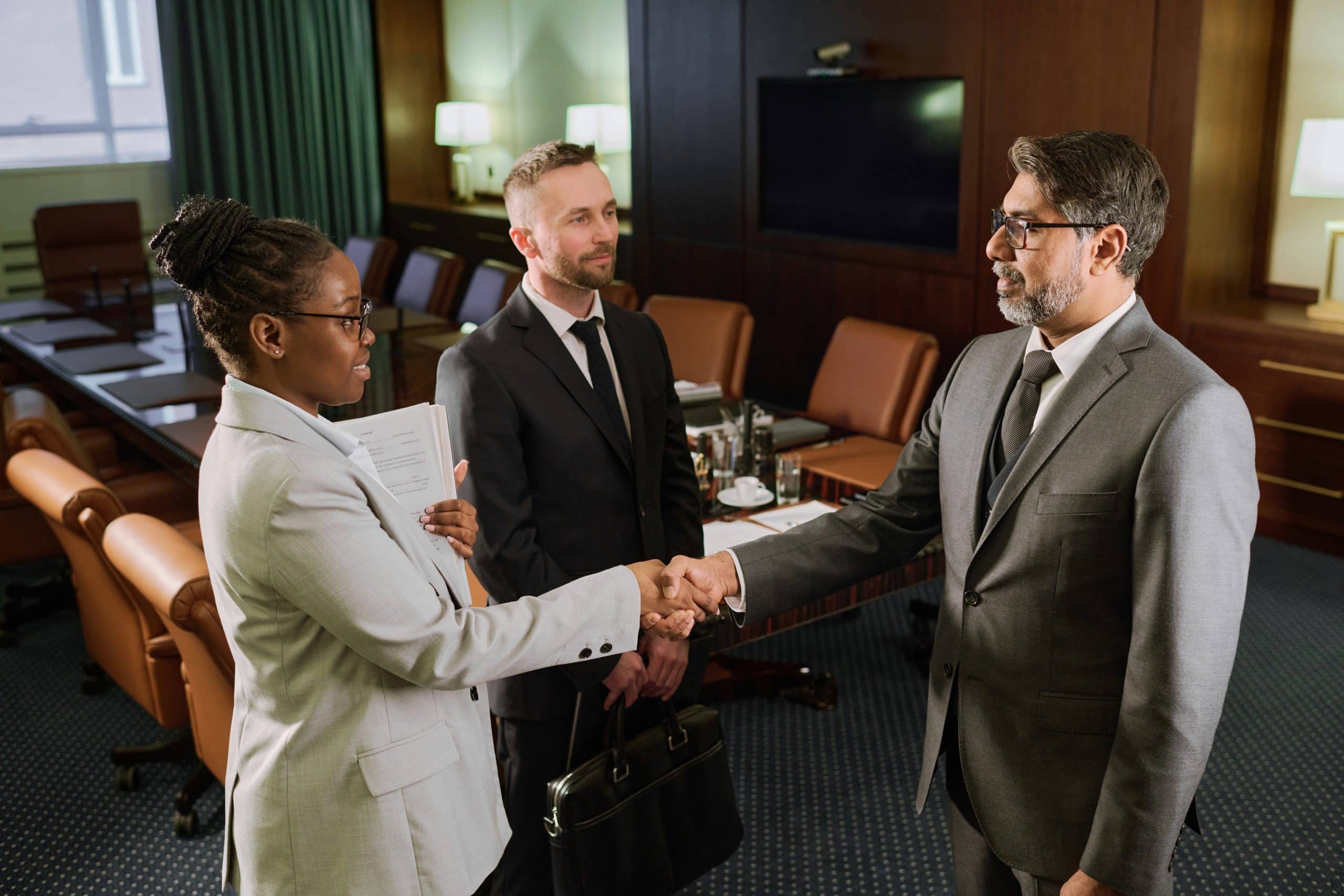 Businesspeople shaking hands in conference room.