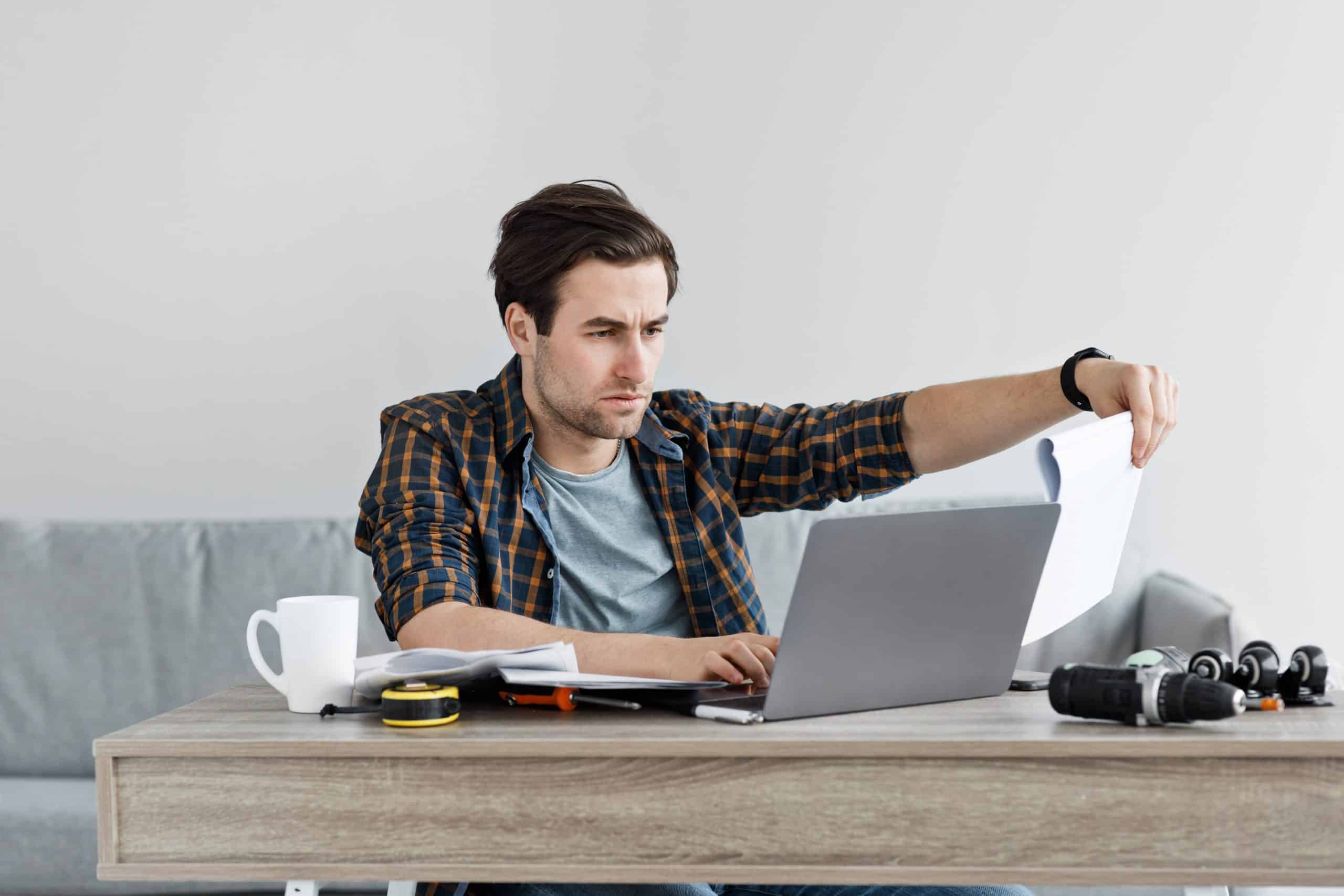 Man working on laptop with tools on desk.