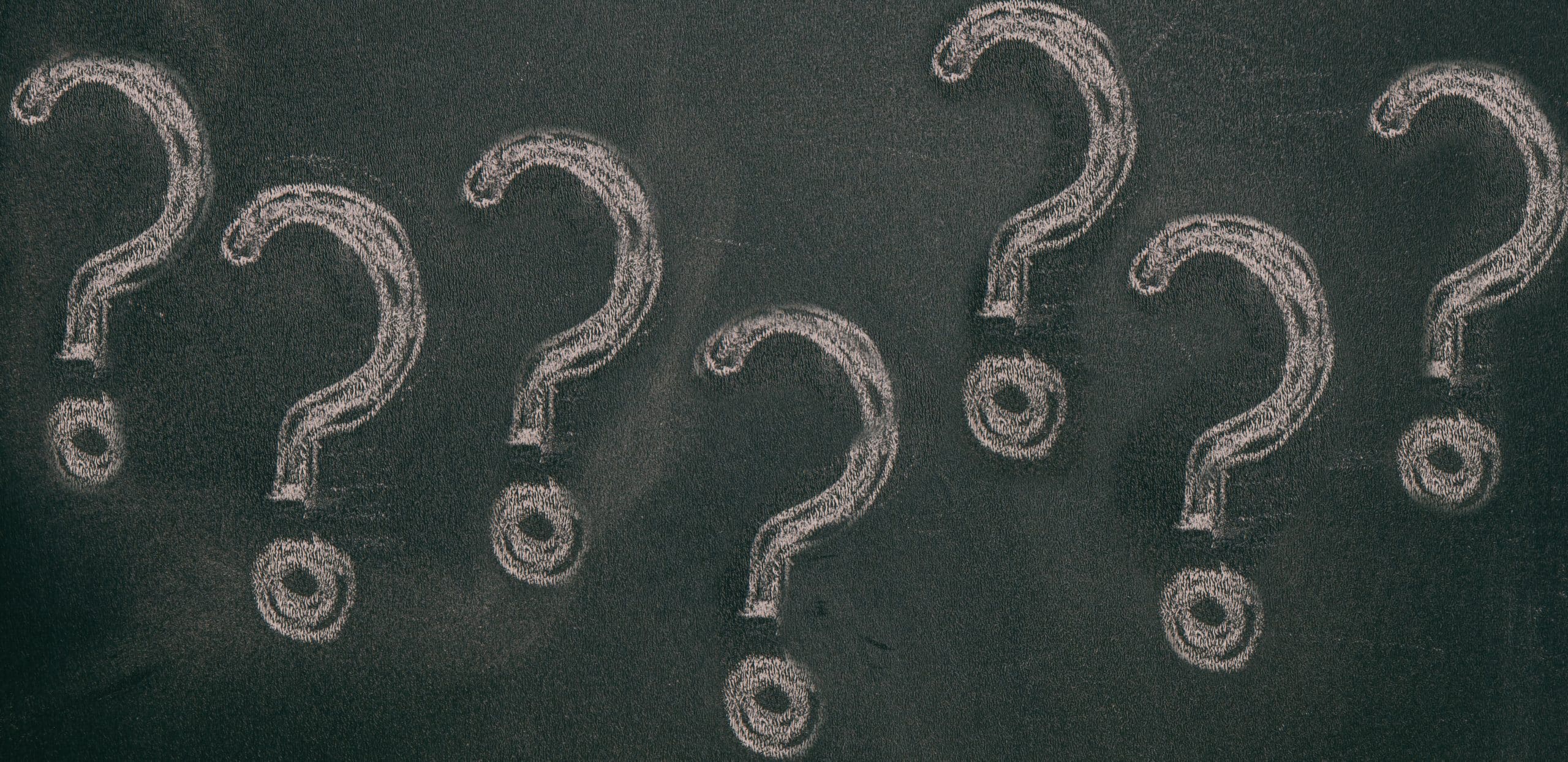Chalk question marks on blackboard