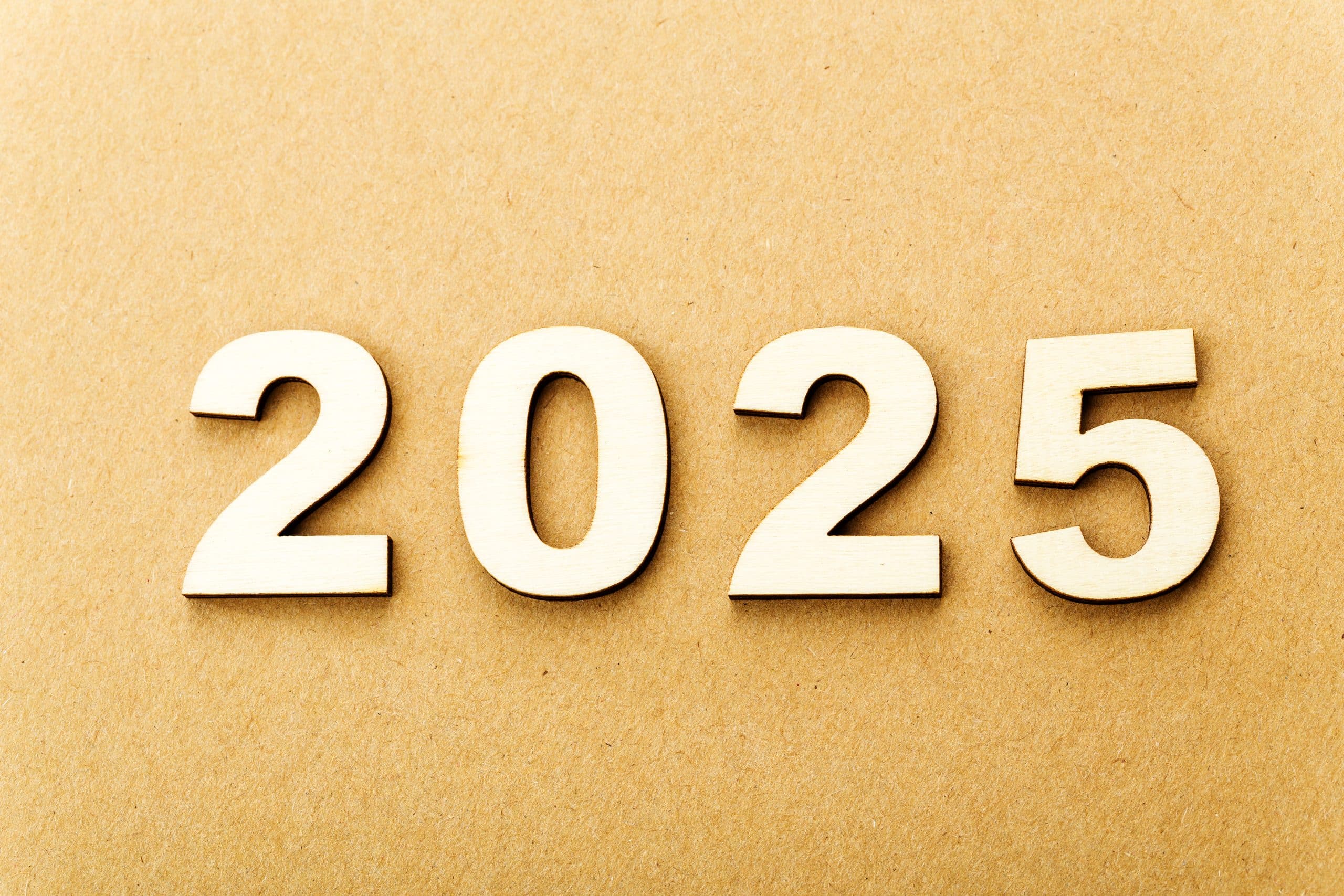 Wooden numbers spelling 2025 on brown background.