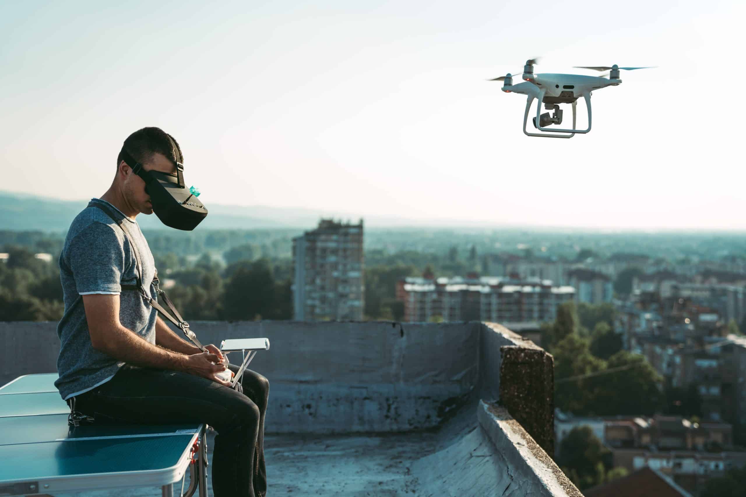 Person flying drone with VR headset on rooftop.