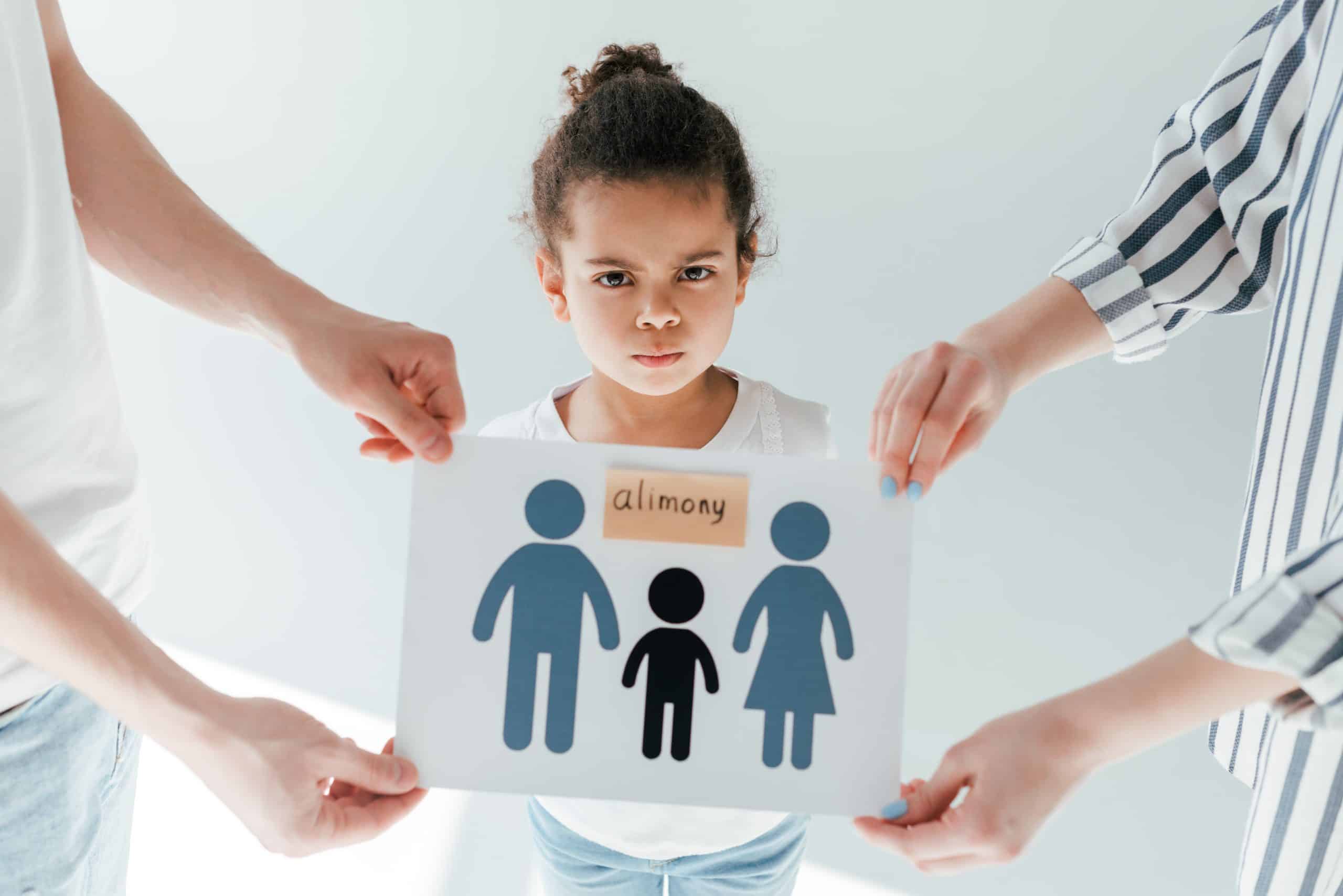 Child between parents holding alimony sign.