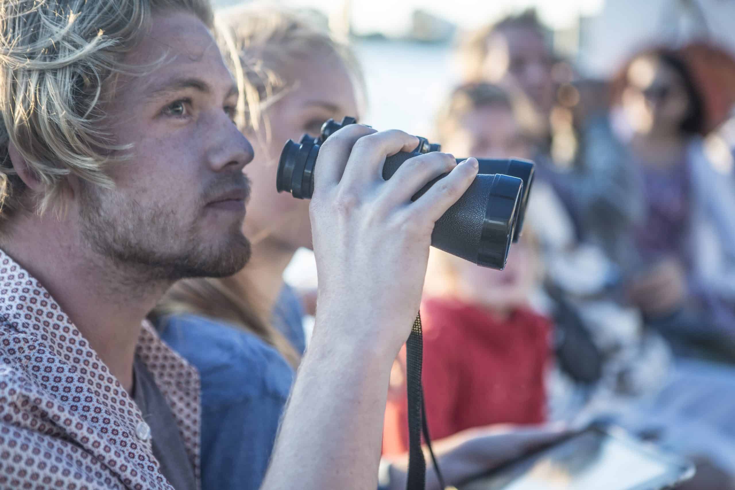Person looking through binoculars on sunny day.