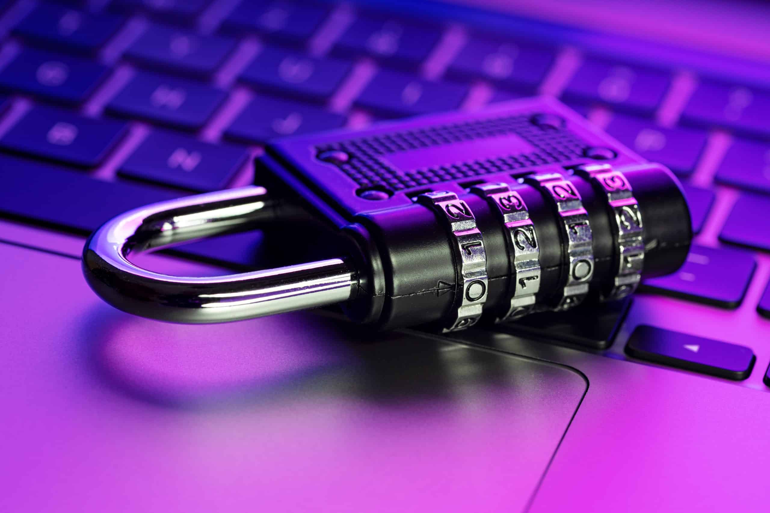 Combination lock on laptop keyboard, cybersecurity concept.