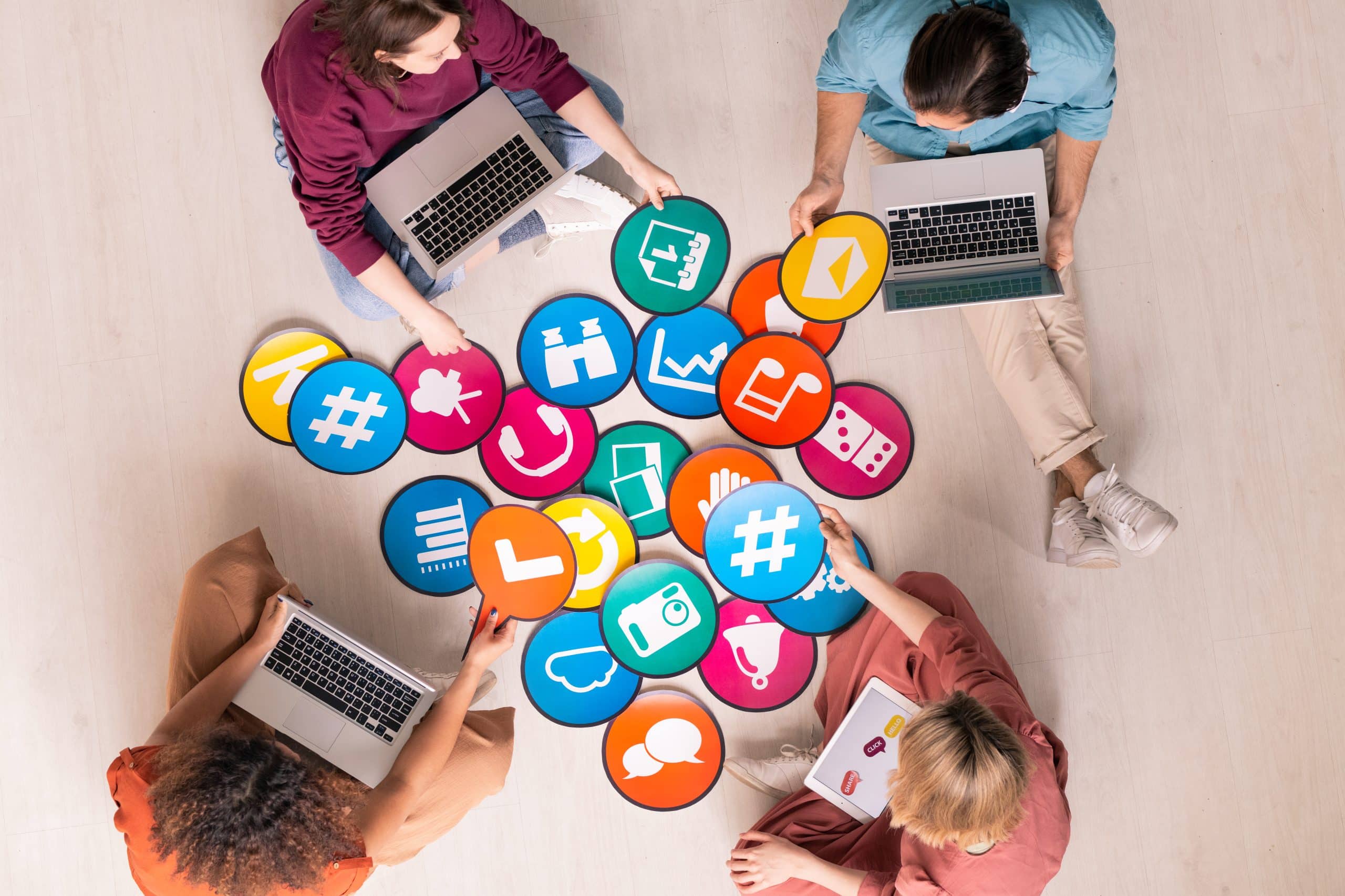 People with laptops organizing colorful social media icons.