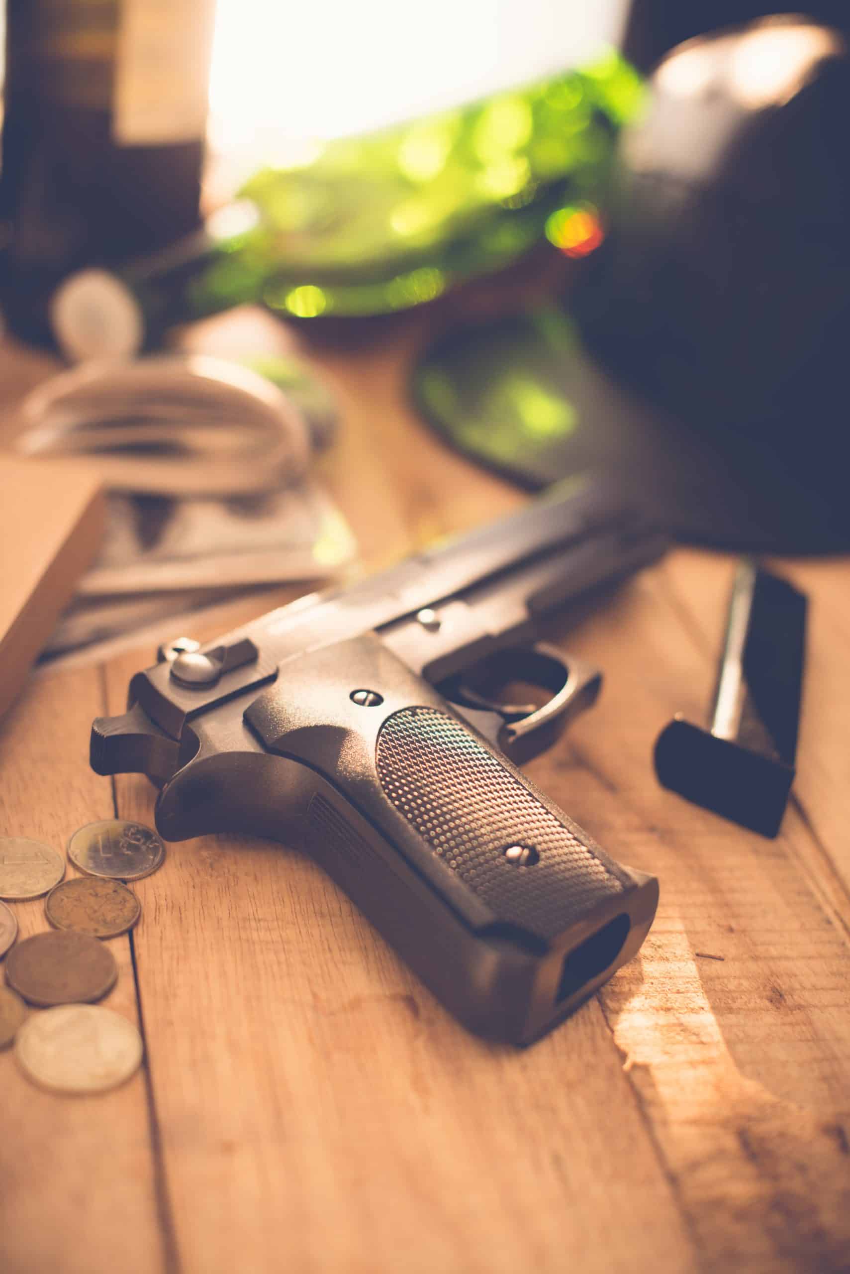 Handgun on wooden table with coins and magazine.