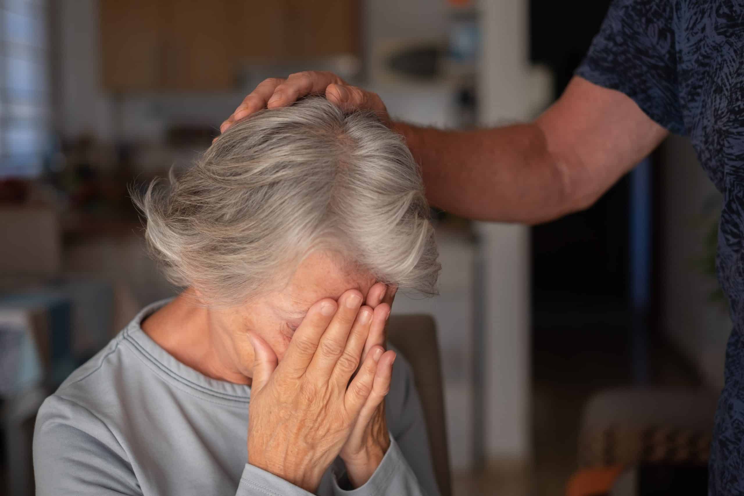 Person comforting elderly woman in distress.